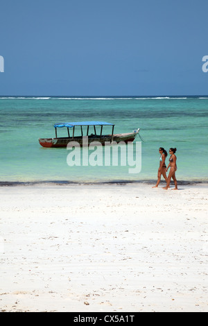 Due giovani donne di camminare sulla spiaggia tropicale, Bwejuu, Zanzibar, Tanzania Africa Foto Stock