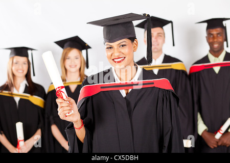 Felice femmina laureato indiano con i compagni di classe a graduazione Foto Stock