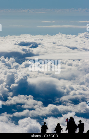 Silhouette di un gruppo di escursionisti in lontananza sulla cima del Monte Fuji sullo sfondo di un mare di nuvole e cieli blu. Foto Stock