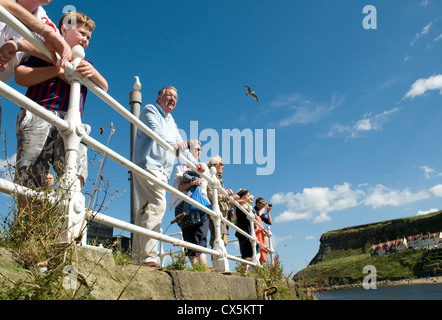Persone che guardano i siti di Whitby Harbour su un blu luminoso giorno d'estate. Foto Stock