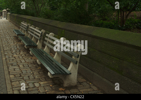 Una fila di panchine lungo la Central Park sul lato ovest di New York City su un marciapiede in ciottoli Foto Stock