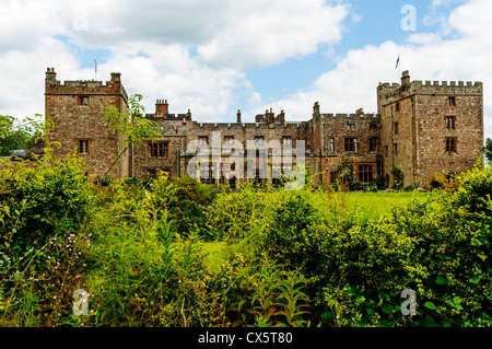 La storica facciata medievale di Muncaster Castle con le sue due torri merlate impostate nei verdi boschi della zona del Lago Foto Stock