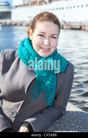 Giovani gioiosi donna russa in piedi sul terrapieno con enormi navi da crociera sullo sfondo, San Pietroburgo, Russia Foto Stock