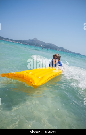 Un giovane ragazzo avente piastre di divertimento nel navigare in mare su di una zattera gonfiabile lilo Foto Stock