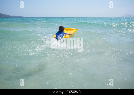 Un giovane ragazzo pagaie in mare su una zattera gonfiabile lilo Foto Stock