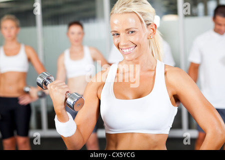 Giovane donna fitness dumbbell facendo esercizio in palestra Foto Stock