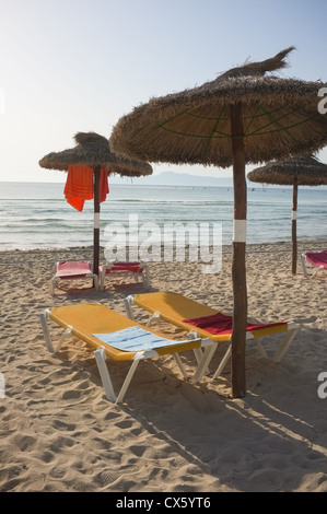 Una spiaggia vuota con asciugamani sui lettini e sfumature Foto Stock