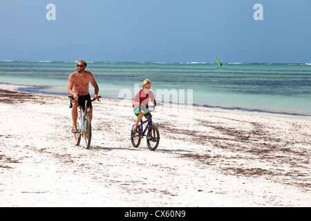 Padre e figlio in bicicletta sulla spiaggia in vacanza Bjewuu, Zanzibar Africa Foto Stock