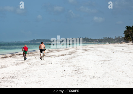 Un padre e figlio in bicicletta sulla spiaggia Bwejuu, Zanzibar Africa Foto Stock