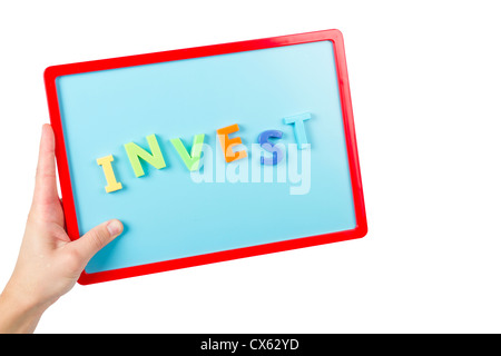 La parola "Invest" enunciato con le lettere magnetiche su un kids scheda magnetica. Foto Stock