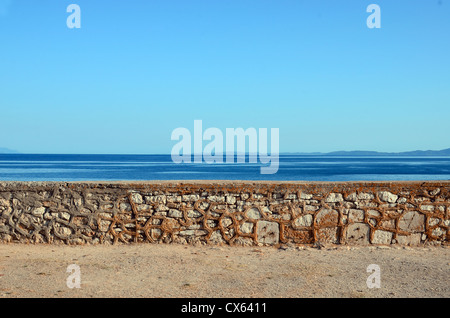 Parete di ciottoli contro il mare e il cielo Foto Stock