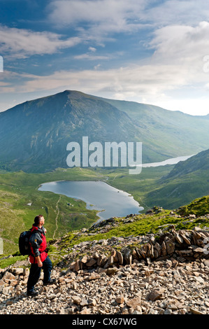 Walker Climbing Glyder Fawr sopra Llyn Idwal, Snowdonia National Park, North Wales, Regno Unito Foto Stock