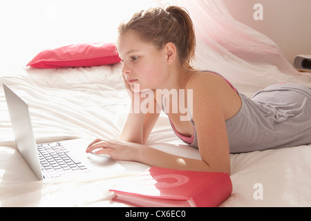 Ragazza sul letto facendo i compiti di scuola Foto Stock