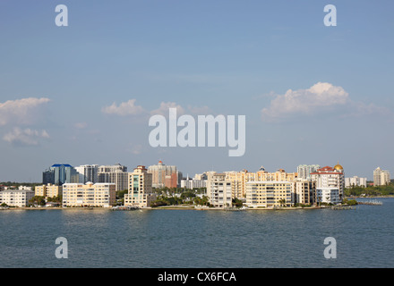 Vista degli edifici sul bordo di Sarasota Bay, Sarasota, Florida da sopra l'acqua con palme, cielo blu e nuvole bianche Foto Stock