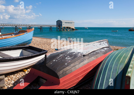 Barche sulla spiaggia Selsey con stazione di salvataggio in background, West Sussex, Regno Unito. Foto Stock