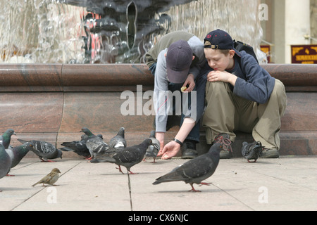 Ragazzi piccioni di alimentazione su la Giornata della vittoria di fronte al Teatro Bolshoi di Mosca, Russia Foto Stock