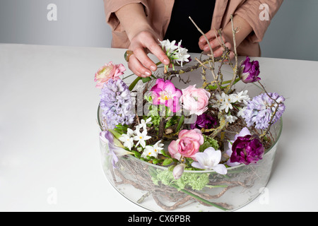 Un fiorista disponendo dei fiori in un vetro vaso intestinale Foto Stock