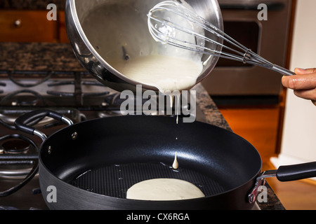 Versando pastella di frittella dolce in padella con fornelli in background Foto Stock