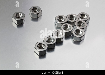 Due dadi di metallo accanto a un gruppo di dadi disposti in un segno di freccia Foto Stock