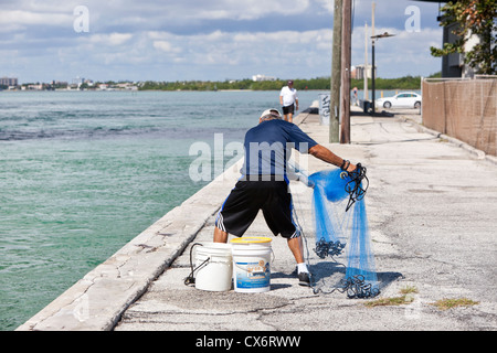 Fisherman che sta per gettare la rete di getto dalla terra, Haulover Park Bayside, Miami, Florida, Stati Uniti Foto Stock