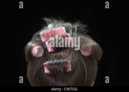 Vista posteriore di una donna con bigodini in her hair Foto Stock