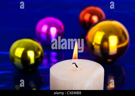 Close up christmas candle e coloratissime palle lucido su sfondo blu. Foto Stock