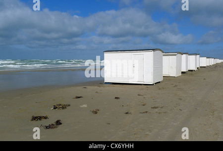 Cabine balneari lungo la spiaggia sabbiosa di Blokhus Jutland in Danimarca con onde che si infrangono nel Mare del Nord su di un ventoso giorni di autunno Foto Stock