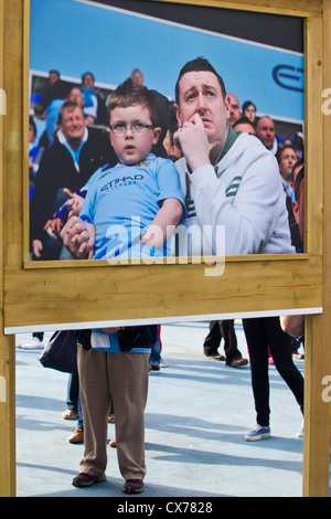 Tifosi guardare la foto-boards fuori l'Etihad Stadium e Manchester City Football Club, Manchester, Inghilterra, Regno Unito Foto Stock