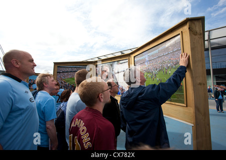 Tifosi guardare la foto-boards fuori l'Etihad Stadium e Manchester City Football Club, Manchester, Inghilterra, Regno Unito Foto Stock