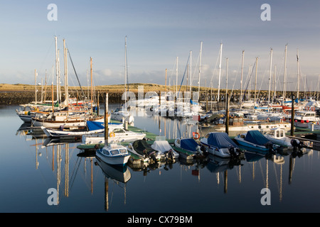 Barche ormeggiate nel camminare marina sulla costa di Northumberland sono riflesse nella ancora la luce del mattino Foto Stock