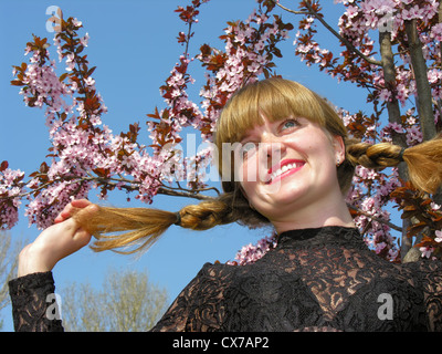Giovani allegro freckled redheaded donna vicino alla struttura di fioritura Foto Stock