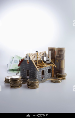 Un parzialmente costruita casa con l'Unione europea valuta e monete intorno ad esso Foto Stock