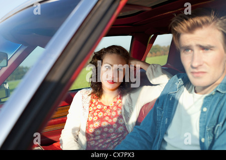 Una bella ragazza rockabilly guardando il fidanzato in irritazione seduti in auto d'epoca Foto Stock