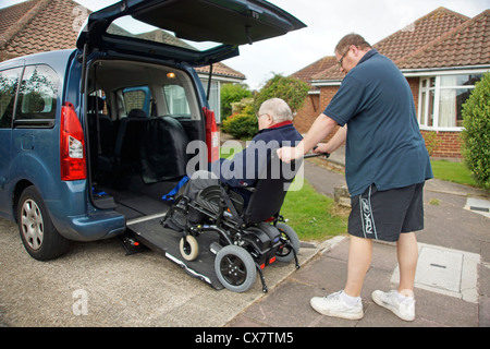 Caregiver maschio figlio spingendo un disabile uomo anziano in una sedia a rotelle su un costruito in rampa in un appositamente auto adattata per ottenere circa Foto Stock