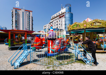 Una giostra e un piccolo parco di divertimenti da università albanese edificio nel centro di Tirana, Albania Foto Stock