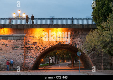 La gente camminare al crepuscolo oltre l'Isabel II (ponte Puente de Triana) a Siviglia Foto Stock