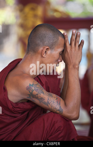 Un monaco in preghiera presso la KUTHODAW PAYA che ospita 729 di lastre di marmo dei Tripitaka - Mandalay, MYANMAR Foto Stock