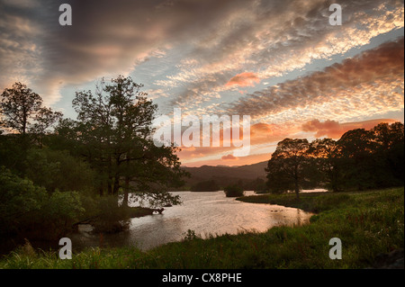 Impostazione sole illumina nuvole sopra Rydal acqua nel Lake District inglese Foto Stock