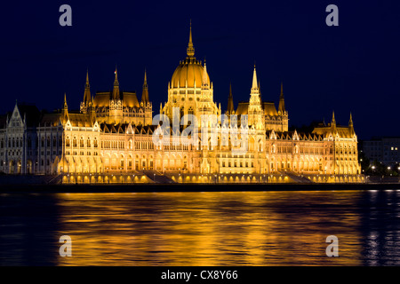 Il Parlamento di Budapest in Ungheria di notte, le riflessioni sul fiume Danubio acque. Foto Stock