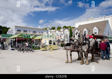 Michigan, isola di Mackinac. Cavallo tradizionale trasporto su vie storiche di Mackinac, noleggio bike shop in distanza. Foto Stock
