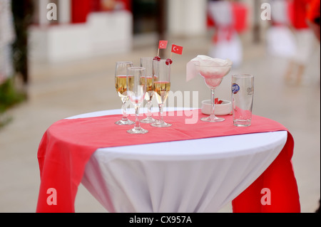 Su un tavolo con una tovaglia bianca e strisce rosse sono gli occhiali con bandiere rosse Foto Stock