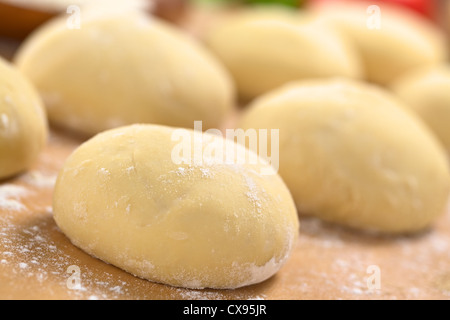 Palline di freschi fatti in casa di pasta per pizza infarinata sulla tavola di legno (fuoco selettivo, la messa a fuoco di un terzo nel primo impasto per pizza) Foto Stock