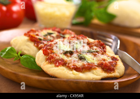 Fragranti pizze Margherita o Pizza Mozzarella (pizza con pomodoro, basilico e formaggio) con la forcella sulla piastra in legno Foto Stock