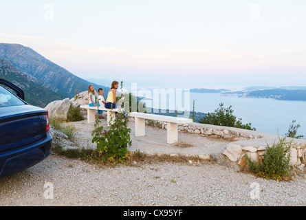 Vista dalla zona di osservazione sul tramonto sul mare e le isole croate e la famiglia sul banco (vicino a Viganj village Foto Stock