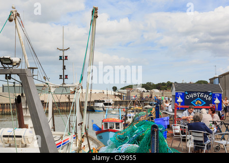 Whitstable Harbour scena con persone cenare presso il bar Oyster sul quay sulla parte settentrionale del Kent e Thames Estuary costa a Whitstable Kent England Regno Unito Foto Stock