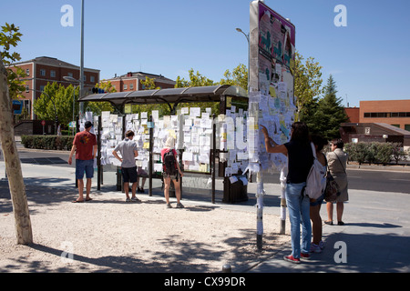 Gli studenti guardando i dettagli per alloggio postato su segni e fermate di autobus vicino all'entrata della metropolitana all'università. Foto Stock