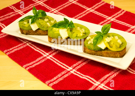 Fresh bruschetta con cimelio di verde formaggio pomodori e basilico sul panno rosso Foto Stock