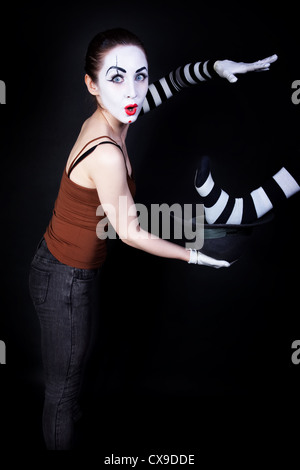 Donna mime di eseguire la messa a fuoco su uno sfondo nero Foto Stock