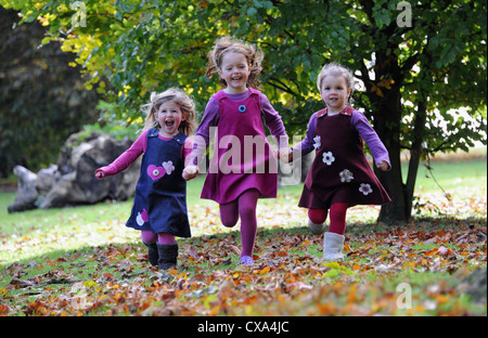 Tre giovani ragazze in esecuzione attraverso foglie autunnali in Hubbard's colline. Foto Stock