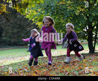 Tre giovani ragazze in esecuzione attraverso foglie autunnali in Hubbard's colline. Foto Stock